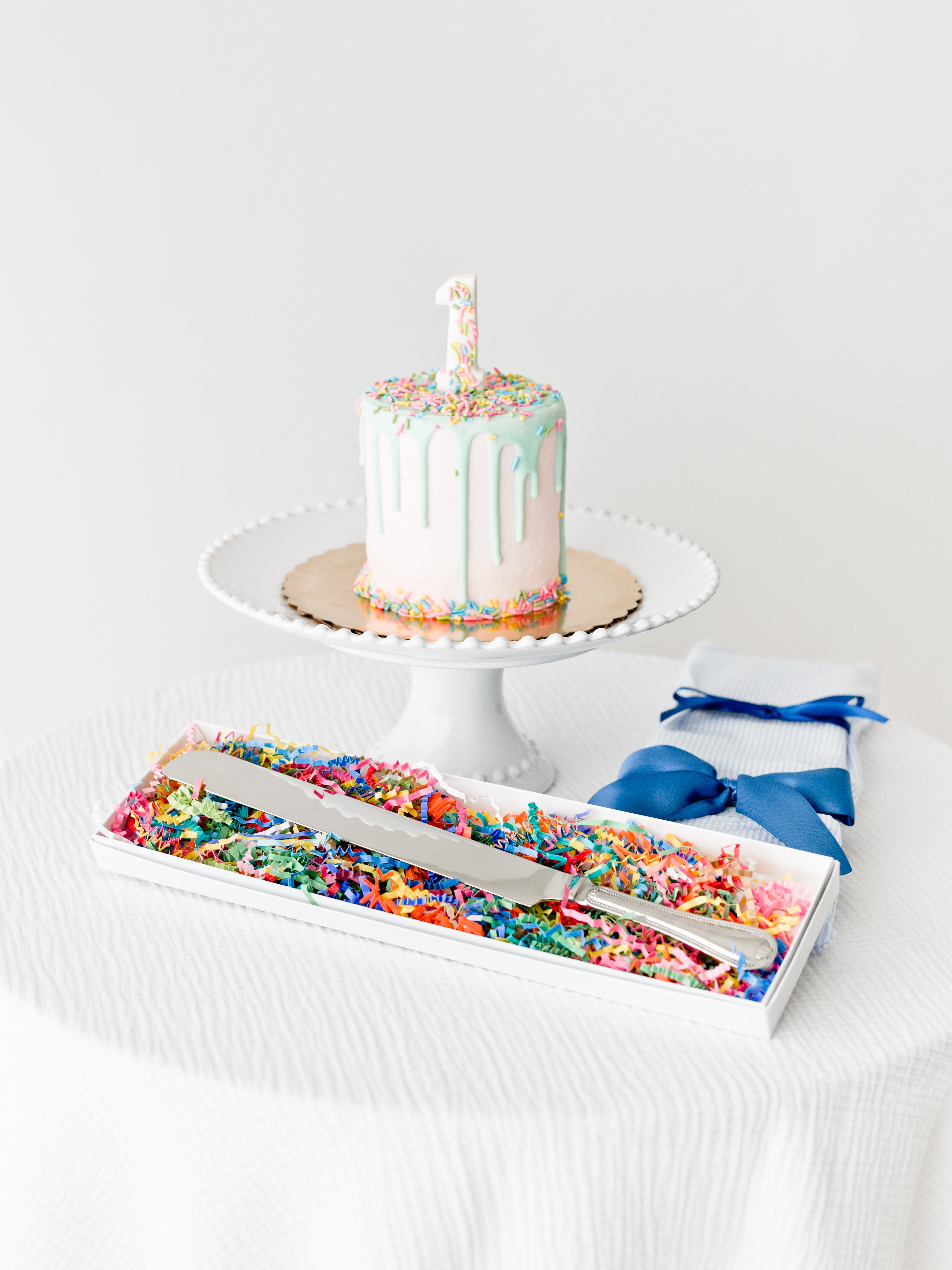 Engraved stainless steel cake knife in keepsake box with colorful shred and blue sleeve.