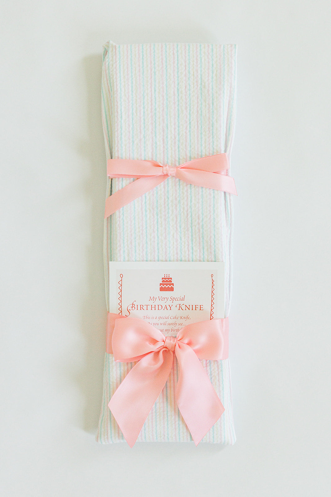 The Pastel Pink Seersucker with Pink Ribbon by Jubilee Keepsakes is a charming cake cutting knife, tied with a pink ribbon and perfect for celebrating special occasions.