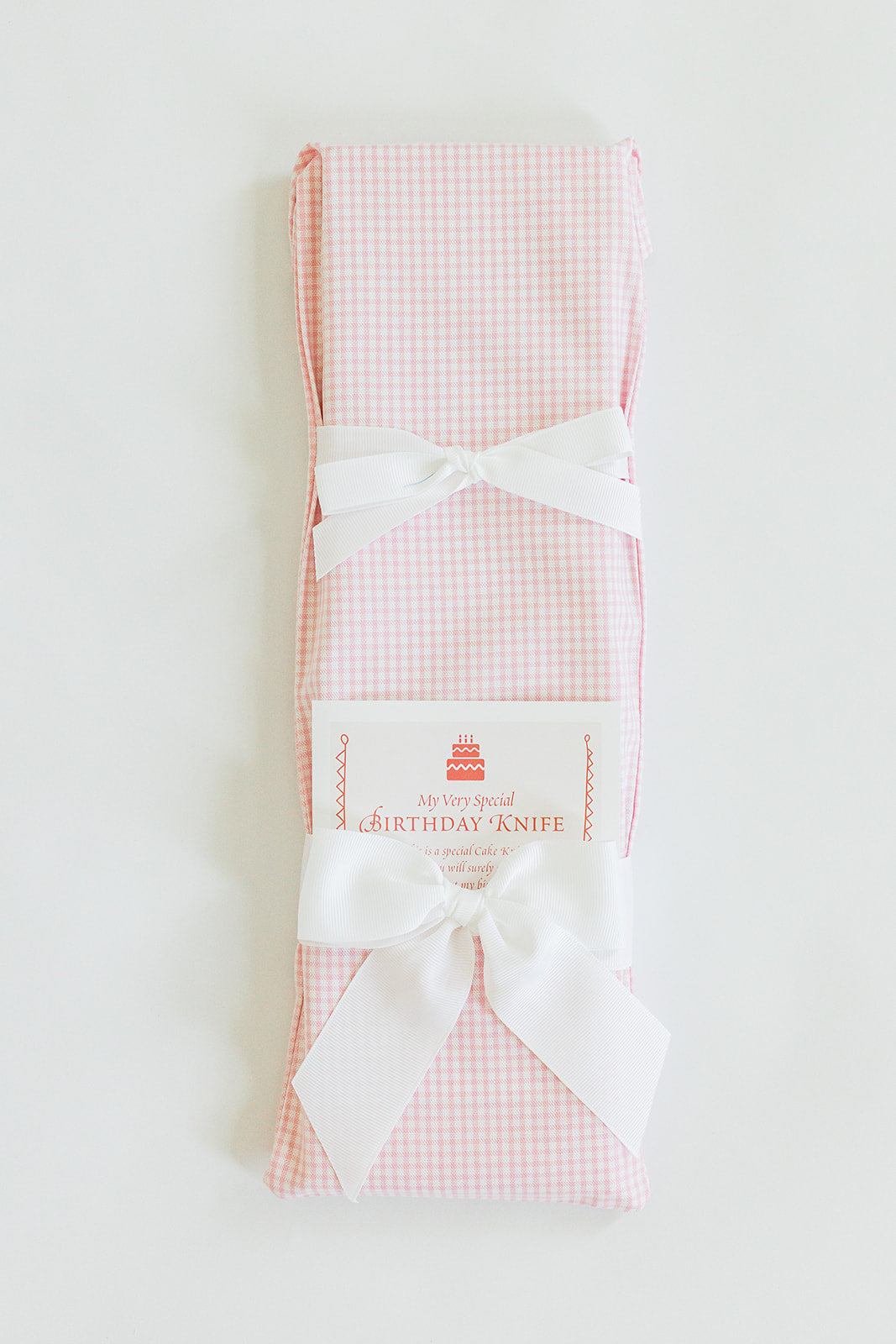 A Jubilee Keepsakes “Tiny Pink Gingham” gift-wrapped cake knife with two white bows and a “My Very Special Birthday Knife” tag—perfect for birthday traditions—displayed against a white background.