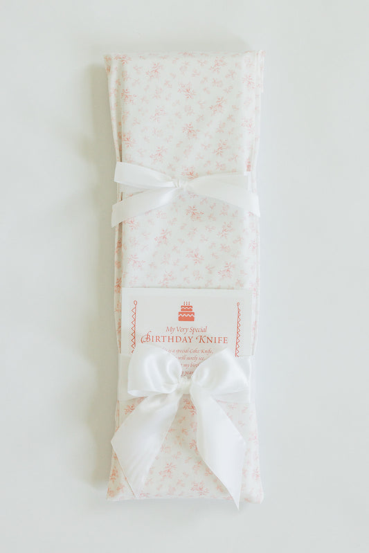 A Jubilee Keepsakes Pink Toile cake-cutting knife, wrapped in floral cloth, tied with a white ribbon and tag reading "My Very Special Birthday Knife.
